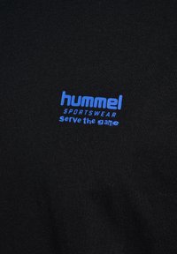 Zwarte katoenen T-shirt met blauwe tekst "hummel SPORTSWEAR" en "Serve the game" in een modern lettertype. Soepele textuur, ronde halslijn.