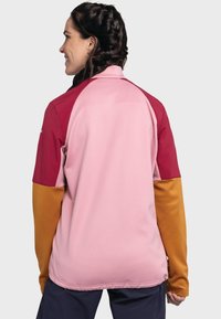 Bunte Jacke mit pinkem Körper, kastanienbraunen Schultern und orangefarbenen Ärmeln. Hergestellt aus einem glatten, leichten Stoff mit langen Ärmeln.