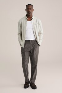 Šviesiai pilka palaidinė su sagomis, balta liemenė, languoti tamsių atspalvių kelnės, rudi zomšiniai batai, palaidinėje yra kišenė, laisvo kirpimo.