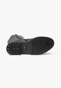 Black leather boot with a rugged rubber sole. Features horizontal grooves and a textured design, suitable for various terrains.