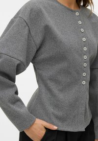 Šedá texturovaná halenka s kulatým výstřihem, dlouhými rukávy a osmi knoflíky po celé přední straně, s přiléhavým střihem.