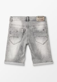 Pantalones cortos de mezclilla gris con dobladillos enrollados, que cuentan con dos bolsillos traseros y una etiqueta de cuero en la cinturilla con detalles de la marca.