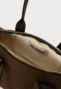 Καφέ υφασμάτινη τσάντα με μαύρες λαβές, ανοιχτό φερμουάρ αποκαλύπτει κρεμ φόδρα και ετικέτα "RUE de VERNEUIL" στο εσωτερικό.