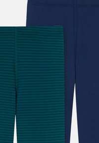 Legginsy w ciemnym granacie i ciemnej zieleni z poziomymi paskami. Gładka faktura, elastyczny materiał i widoczne szwy.