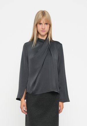 Donkergrijze blouse met lange mouwen en een gedrapeerde halslijn. Gemaakt van een gladde stof met een lichte glans. Heeft zijsplitten aan de zoom.