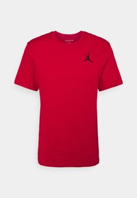 T-shirt rossa in cotone con collo rotondo. Presenta un piccolo logo Jumpman nero sul lato sinistro del petto. Maniche corte e vestibilità regolare.