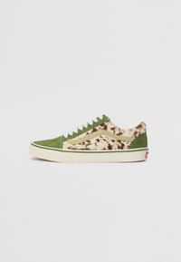 Zapatillas de ante verde con un panel suave en tonos marrón y crema salpicados. Cintas blancas, suela color marfil y detalles verdes en la entresuela.