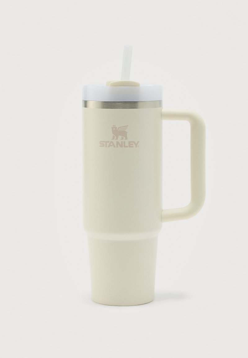 Κρεμ θερμός ταξιδιού Stanley με λαβή, καπάκι και λευκό καλαμάκι, εμφανίζεται σε απλό λευκό φόντο.