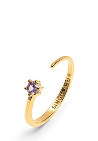 Anillo de tono dorado con un diseño abierto, que presenta una piedra preciosa redonda de color lavanda engastada en garras. Grabado con "SINGULARU" en la banda.