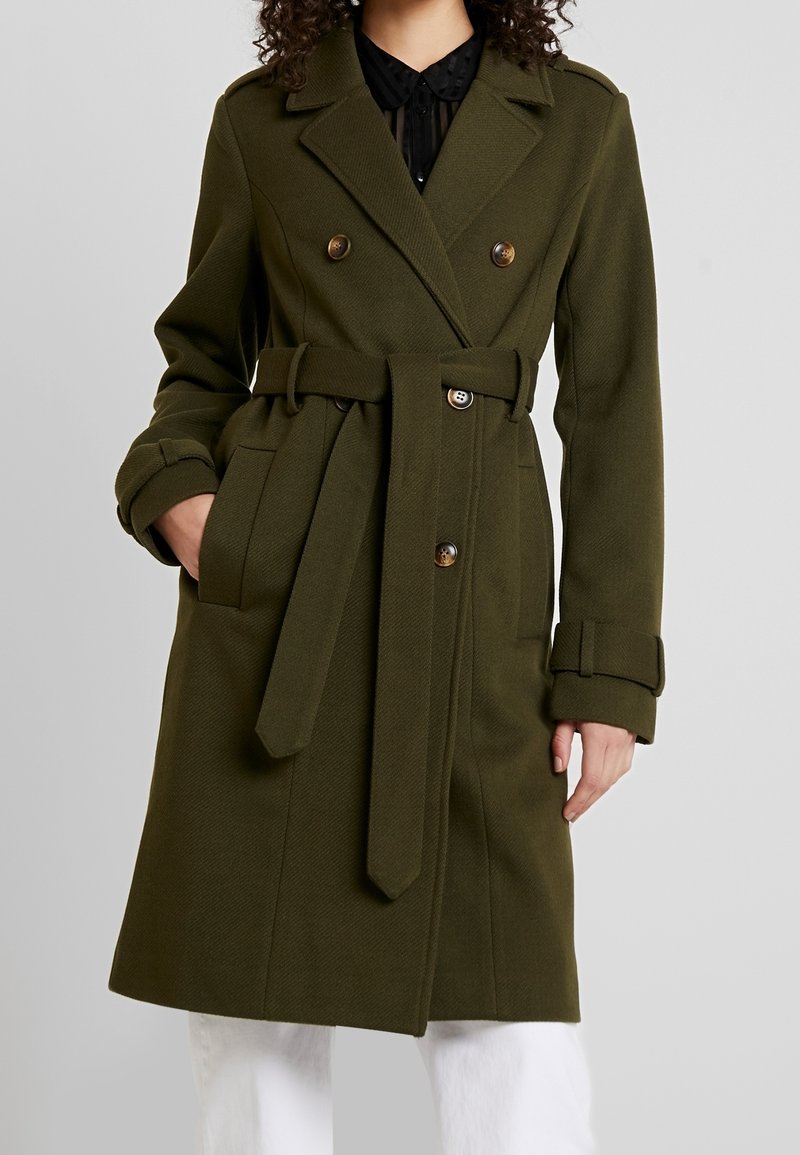 Olijfgroene, dubbelgeknoopte trenchcoat met een ceintuur in de taille, gestructureerde stof en knoopdetails aan de voorkant en op de mouwen.