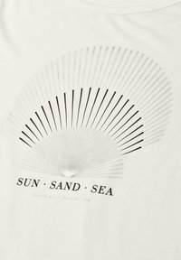Fan-shaped graphic with radiating lines in black and gray above the text "SUN SAND SEA" on a white fabric background.