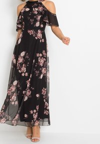 Svart maxi klänning med korta kalla axelärmar, volangdetaljer och mönster av rosa rosor. Lätt och flödande tyg. Enkla skor.