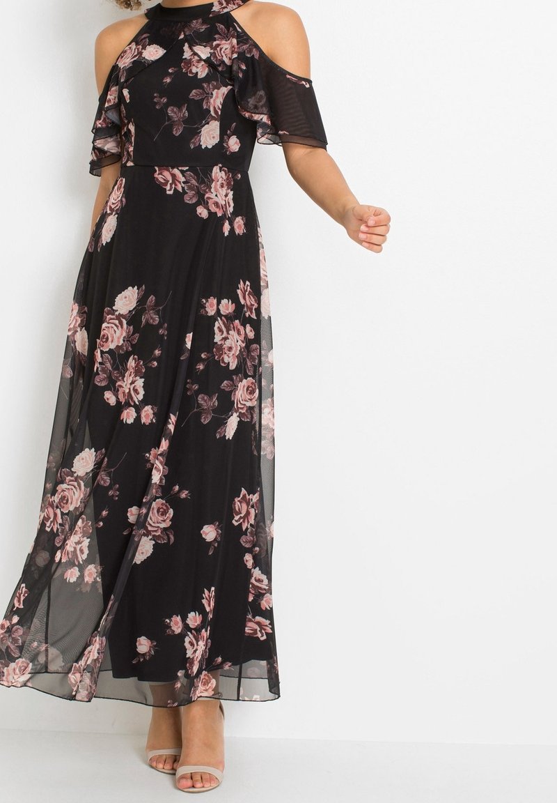 Svart maxi klänning med korta kalla axelärmar, volangdetaljer och mönster av rosa rosor. Lätt och flödande tyg. Enkla skor.