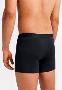 Black cotton boxer briefs with a soft elastic waistband featuring subtle branding. Smooth texture and fitted design.