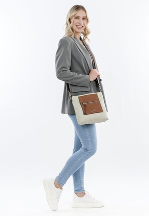 Beige crossbody bag with brown accents, zippered front pocket, and adjustable strap. Smooth fabric with subtle sheen and structured shape.