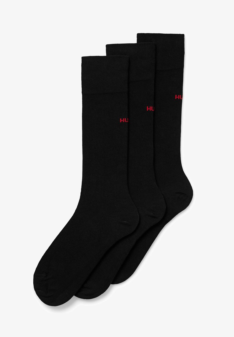 Black cotton socks in a pack of three, featuring ribbed cuffs and small red "HUGO" logo on the side. Soft, smooth texture.