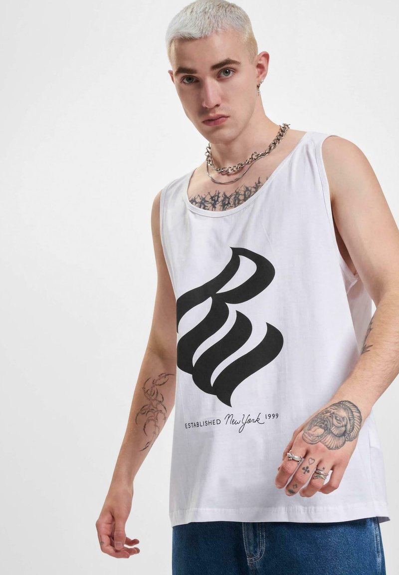 Top din bumbac alb, cu un mare logo grafic negru și textul "ESTABLISHED New York 1999." Purtați cu blugi; design minimalist.