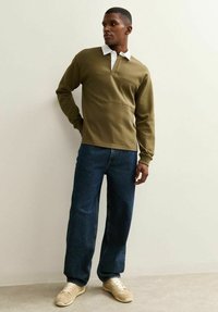 Khaki long-sleeve polo shirt with a white collar, paired with dark blue straight-leg jeans and cream sneakers. Simple, minimalistic design.