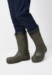 Dark green waterproof rubber boots with a textured surface, reinforced toe, and adjustable black insulated cuff. Rubber sole with traction.