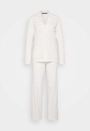 Bílý pyžamový set, který obsahuje sako s výstřihem do V, knoflíkové zapínání a dvě přední kapsy, spolu s rovnými kalhotami. Měkká textura.