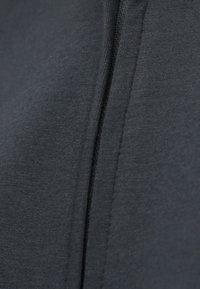 Ύφασμα φούτερ με φερμουάρ σε γκρι απόχρωση, με λεία υφή, διαθέτοντας κεντρικό φερμουάρ και ραμμένα διακοσμητικά στις ραφές.