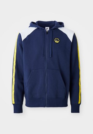 Navy zip-up hoodie with white shoulder accents, yellow side stripes featuring logo, and front pockets. Made from a soft fabric.