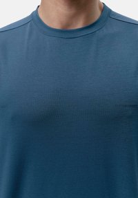 T-shirt z mieszanki bawełny w ciemnoniebieskim kolorze, z okrągłym dekoltem i subtelnymi detalami tekstowymi "ŚWIATŁO", "WŁĄCZONE", "WODA", "CIĘŻKI", podkreślającymi zrównoważony rozwój.