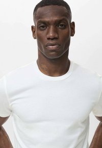 Tricou alb cu mânecă scurtă, confecționat din bumbac moale, având un decolteu rotund ribbed și un design slim fit, fără logo-uri sau modele vizibile.