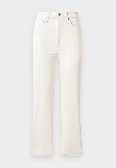 Bijele traperice s visokim strukom, u obliku zvona, sa patentnim zatvaračem, pet džepova i suptilnim detaljima šavova. Tkanina ima glatku teksturu.