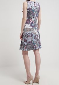 Ärmlös klänning med paisleymönster i lila, teal och krämfärgad; lättviktig tyg; utsvängd silhuett; längd till mitten av låret; sidodragkedja.