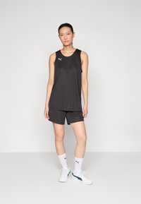 Musta urheilullinen tank top ja shortsit, valmistettu kevyestä materiaalista. Sisältää valkoisen Puma-logon. Yhdistetty valkoisten sukkien ja lenkkareiden kanssa.