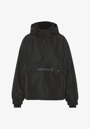 Schwarze Windjacke mit Kapuze, die eine Fronttasche, elastische Bündchen und ein Logo auf der Brust aufweist. Das Material wirkt glatt und wetterbeständig.