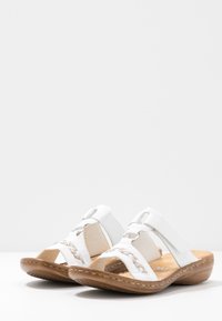 Sandales blanches avec accent tressé et design découpé. Comprend des sangles réglables et une semelle ronde en caoutchouc marron. Semelle intérieure texturée.