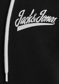 Sort sweatshirt med hvid snøre. Har "Jack & Jones" logo i kursiv hvid tekst foran. Blød stofstruktur.