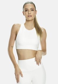 Top corto atlético blanco con cuello alto, combinado con leggings de talle alto a juego. Textura suave, costuras mínimas y diseño elegante.