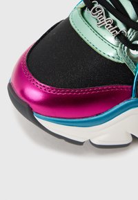 Χοντρό αθλητικό παπούτσι με μαύρο δίχτυ στο πάνω μέρος, μεταλλικές λεπτομέρειες σε τιρκουάζ και φούξια, λευκή σόλα και ασημί λογότυπο στη γλώσσα.