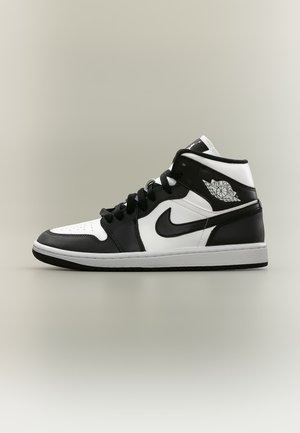 Zapatilla Air Jordan de caña alta en blanco y negro con logo Nike swoosh y logo de alas Air Jordan sobre fondo liso.