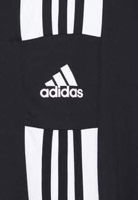 Czarna odzież sportowa z białymi pionowymi paskami; posiada przednią kieszeń oraz wyraźnie widoczne białe logo Adidasa. Tekstura materiału.