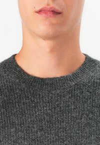 Gray knitted sweater with a textured finish. Features a crew neckline and ribbed trim at the collar, made from a soft wool blend.