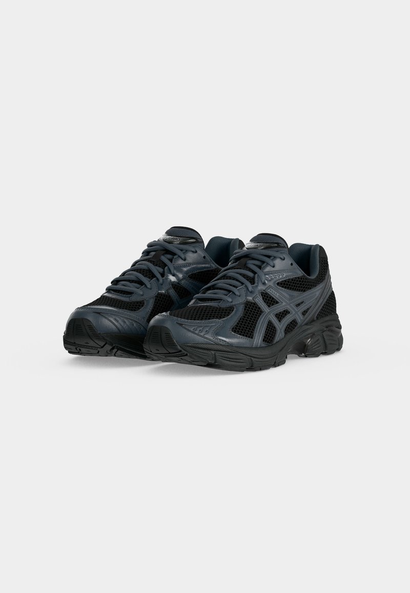 Par de zapatillas de correr de malla negras y gris oscuro con cordones, colocadas lado a lado sobre un fondo blanco.