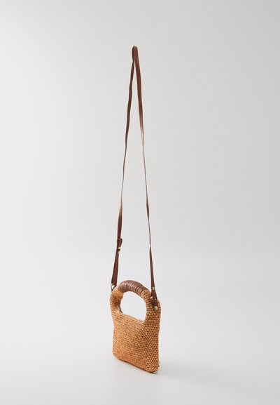 Vevd rattan crossover veske med et brunt lærhåndtak og justerbar stropp. Rektangulær form med en naturlig, strukturert finish.