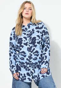 Lange mouwen overhemd met knopen in lichtblauw met een donkerblauw abstract luipaardpatroon. Heeft een ontspannen pasvorm en zachte, lichte stof.
