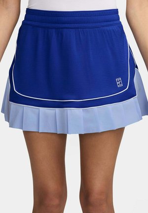 Skort sportif bleu avec un jupon plissé bleu clair porté par une personne aux jambes et au torse visibles.