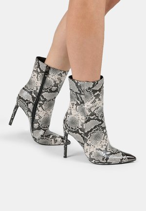 Stivaletti alla caviglia con motivo di pelle di serpente in bianco e nero, dotati di punta affusolata, alto tacco a stiletto e dettagli con zip laterale.