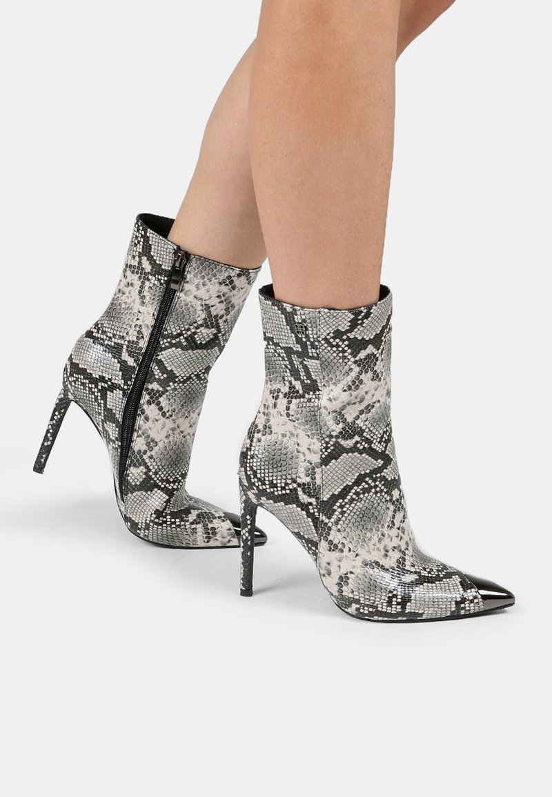 Stivaletti alla caviglia con motivo di pelle di serpente in bianco e nero, dotati di punta affusolata, alto tacco a stiletto e dettagli con zip laterale.