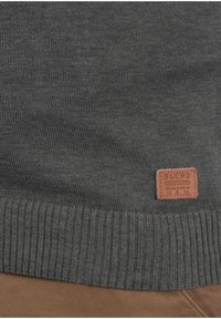 Grauer Strickpullover mit geripptem Saum, strukturiertem Stoff und einem braunen Lederetikett mit dem geprägten Schriftzug "BLEND".