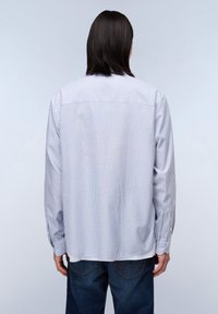 Chemise à rayures à manches longues en coton bleu clair et blanc, dotée d'un empiècement au dos, de poignets boutonnés et d'une coupe décontractée.
