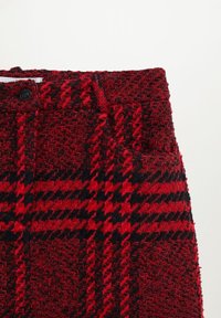Punainen ja musta houndstooth-kuvioinen kangas, jossa on teksturoitu kudos, vyötärönauha ja etupainike.
