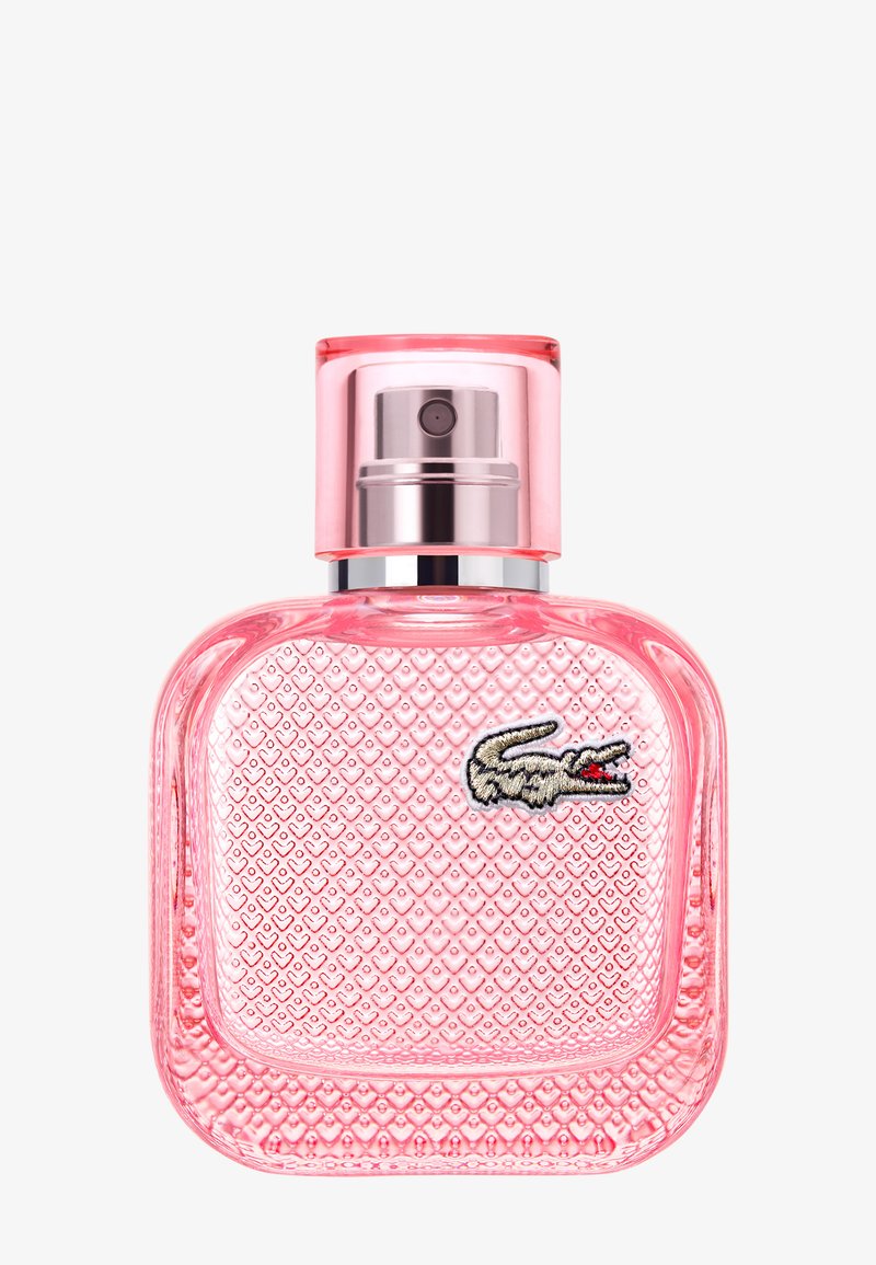 Flacon de parfum en verre texturé rose avec un embout spray argenté et un logo crocodile brodé sur le devant.