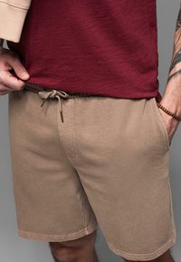 Beige šortky s elastickým pasem a šňůrkou. Měkká látka, boční kapsy a šití na lemu.